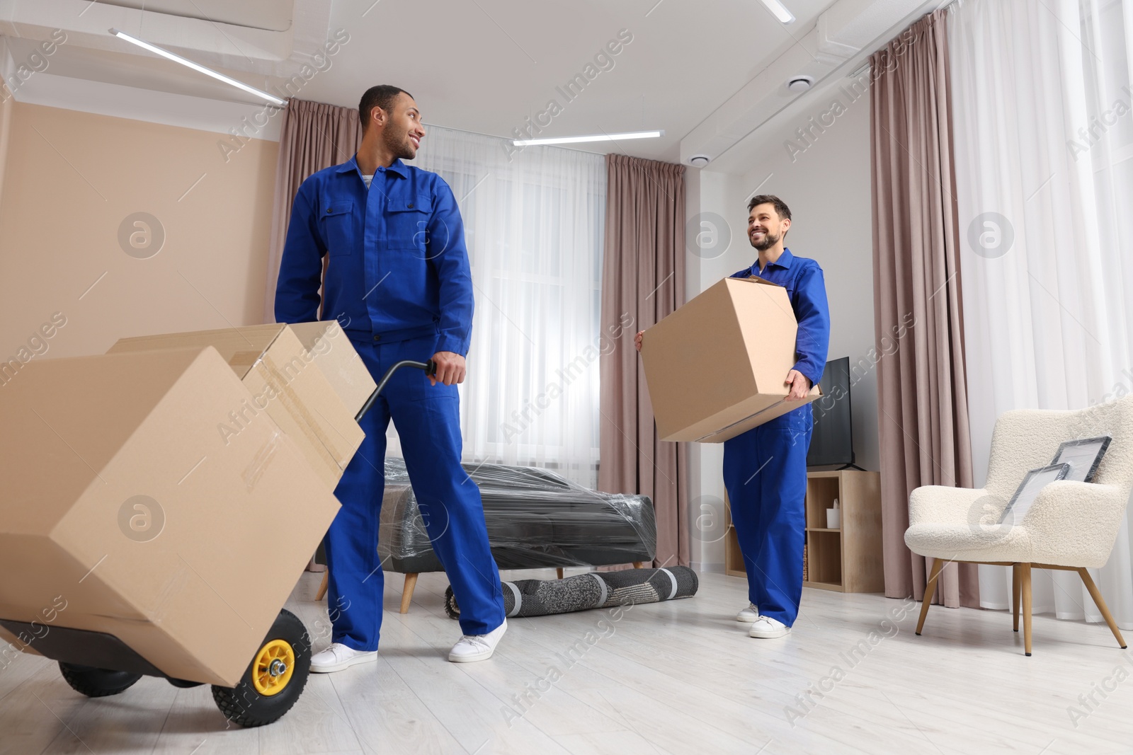 Photo of Male movers with cardboard boxes in new house