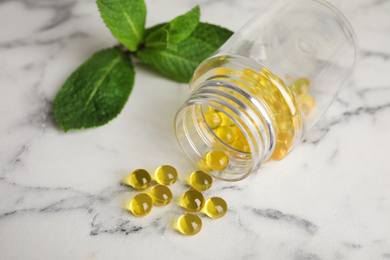 Photo of Bottle with vitamin pills on white marble table, closeup