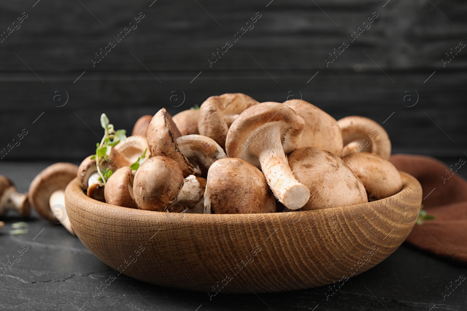 Photo of Fresh wild mushrooms in bowl on black table