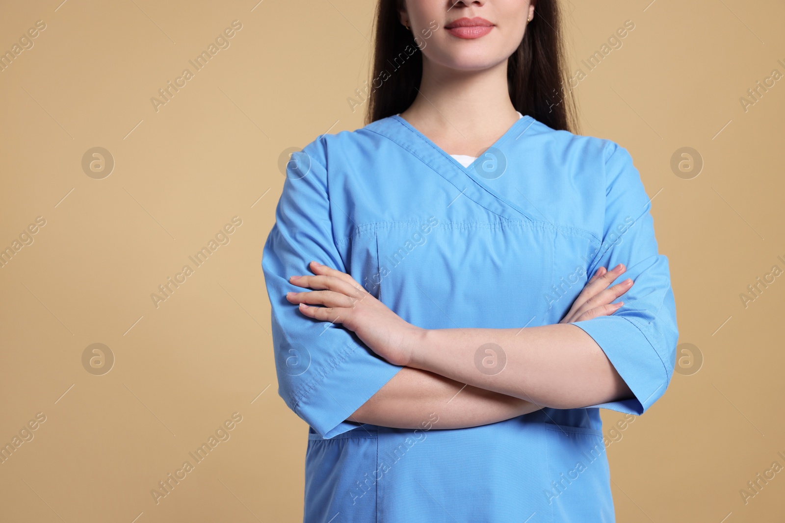 Photo of Nurse in medical uniform on light brown background, closeup. Space for text