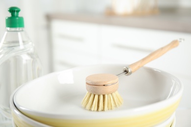 Photo of Cleaning brush for dish washing and bowl indoors, closeup