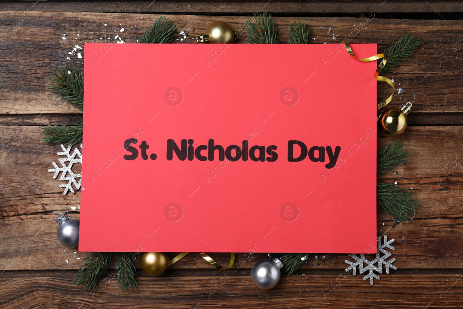 Photo of Red card with text St. Nicholas Day and festive decor on wooden table, flat lay