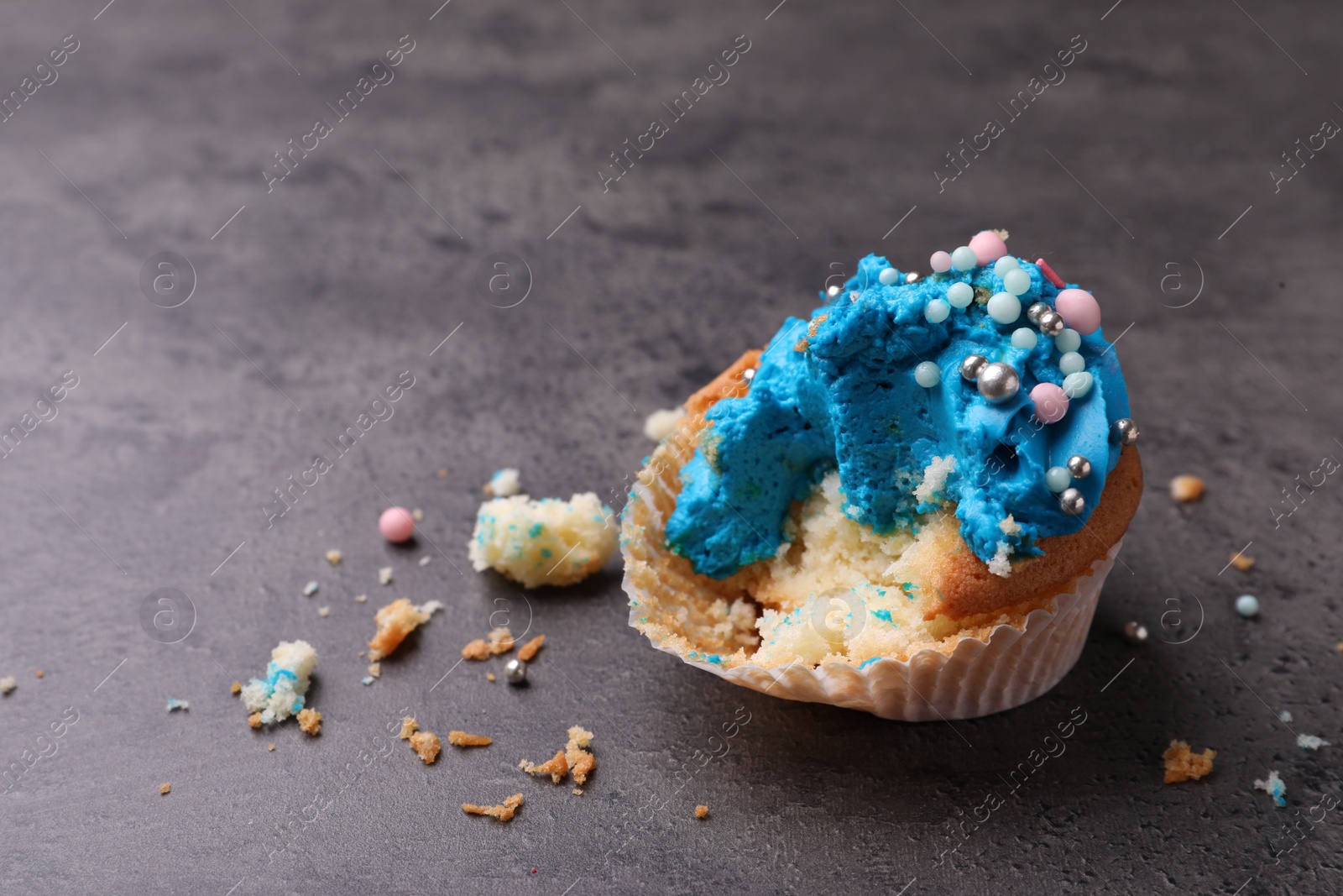 Photo of Failed cupcake with cream on grey table. Troubles happen