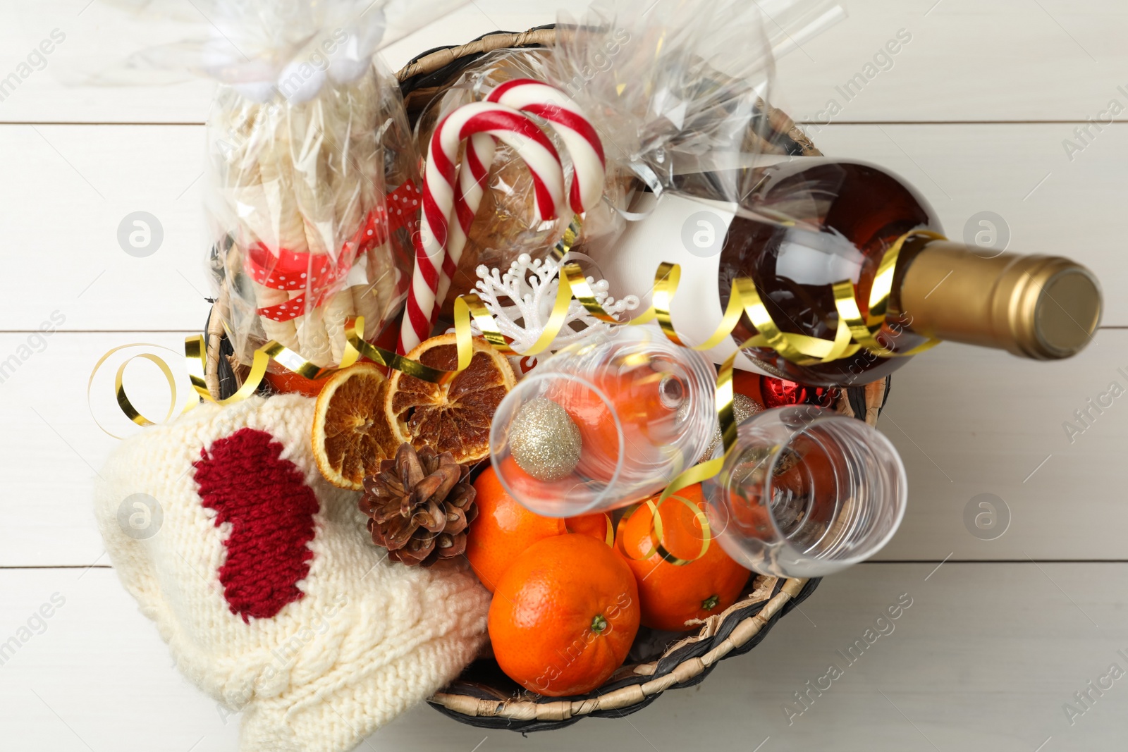 Photo of Wicker basket with Christmas gift set on white wooden table, top view