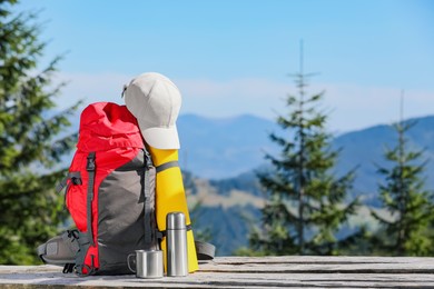 Photo of Backpack and other camping gear on wooden surface outdoors, space for text. Mountain tourism