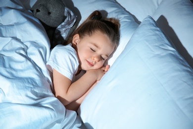 Photo of Beautiful little girl sleeping with toy in bed at night. Bedtime schedule