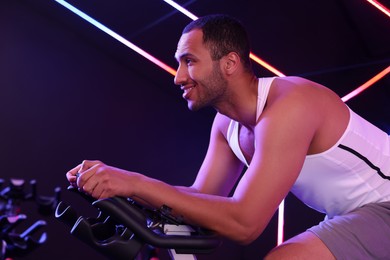 Photo of Young man training on exercise bike in fitness club