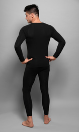 Man wearing thermal underwear on grey background, back view