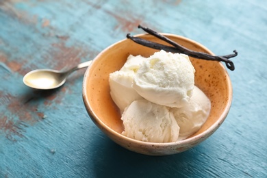 Photo of Bowl with tasty vanilla ice cream on wooden background