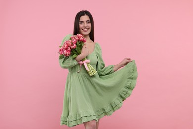 Photo of Happy young woman with beautiful bouquet on dusty pink background