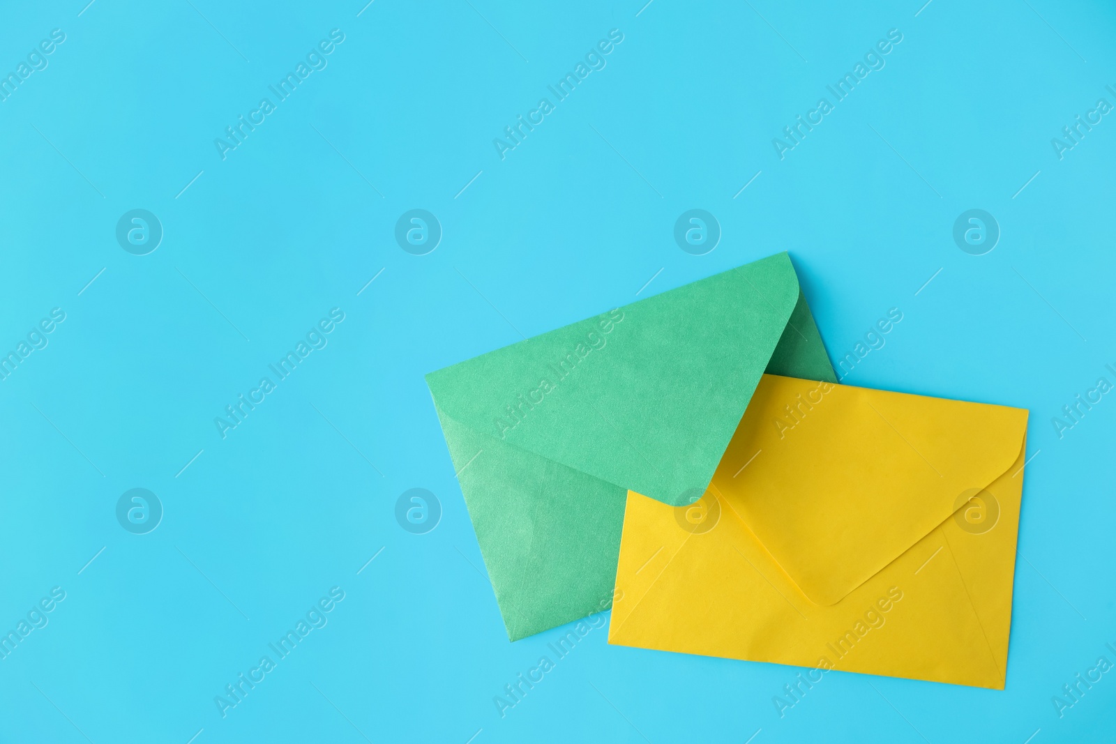 Photo of Colorful paper envelopes on light blue background, flat lay. Space for text