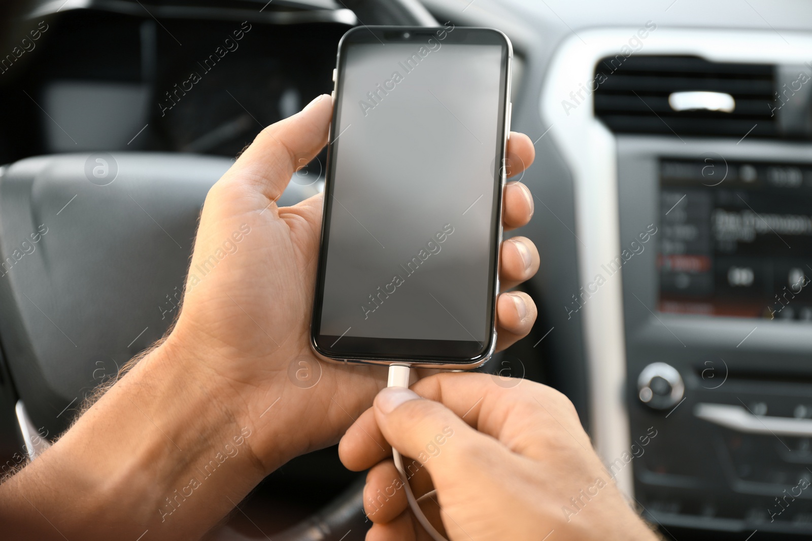 Photo of Man connecting charging cable to smartphone in car, closeup