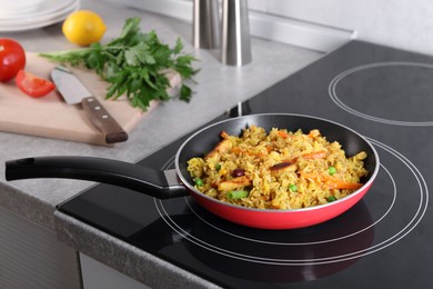 Photo of Tasty rice with meat and vegetables in frying pan on induction cooktop