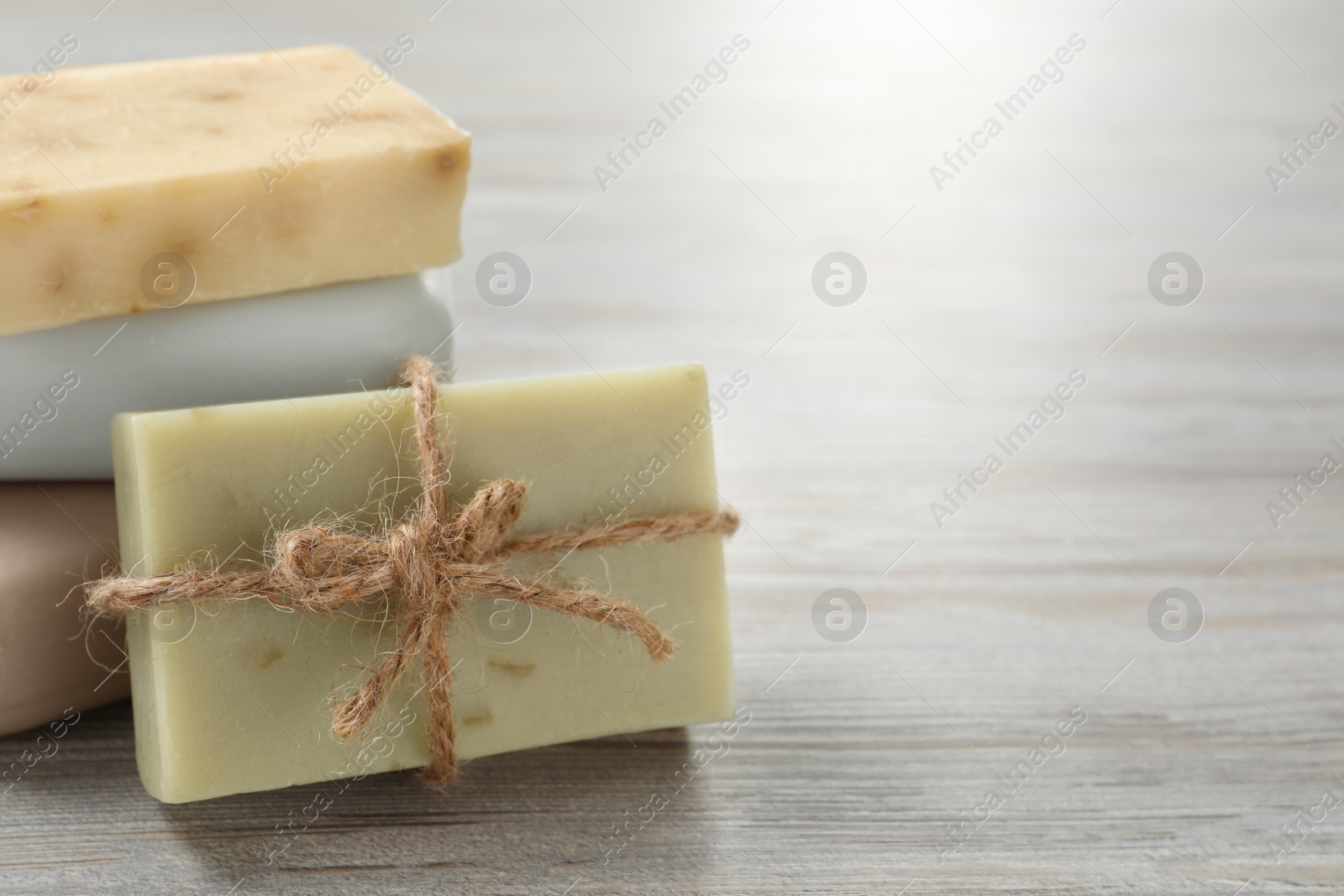 Photo of Stack of different soap bars on white wooden table, closeup. Space for text