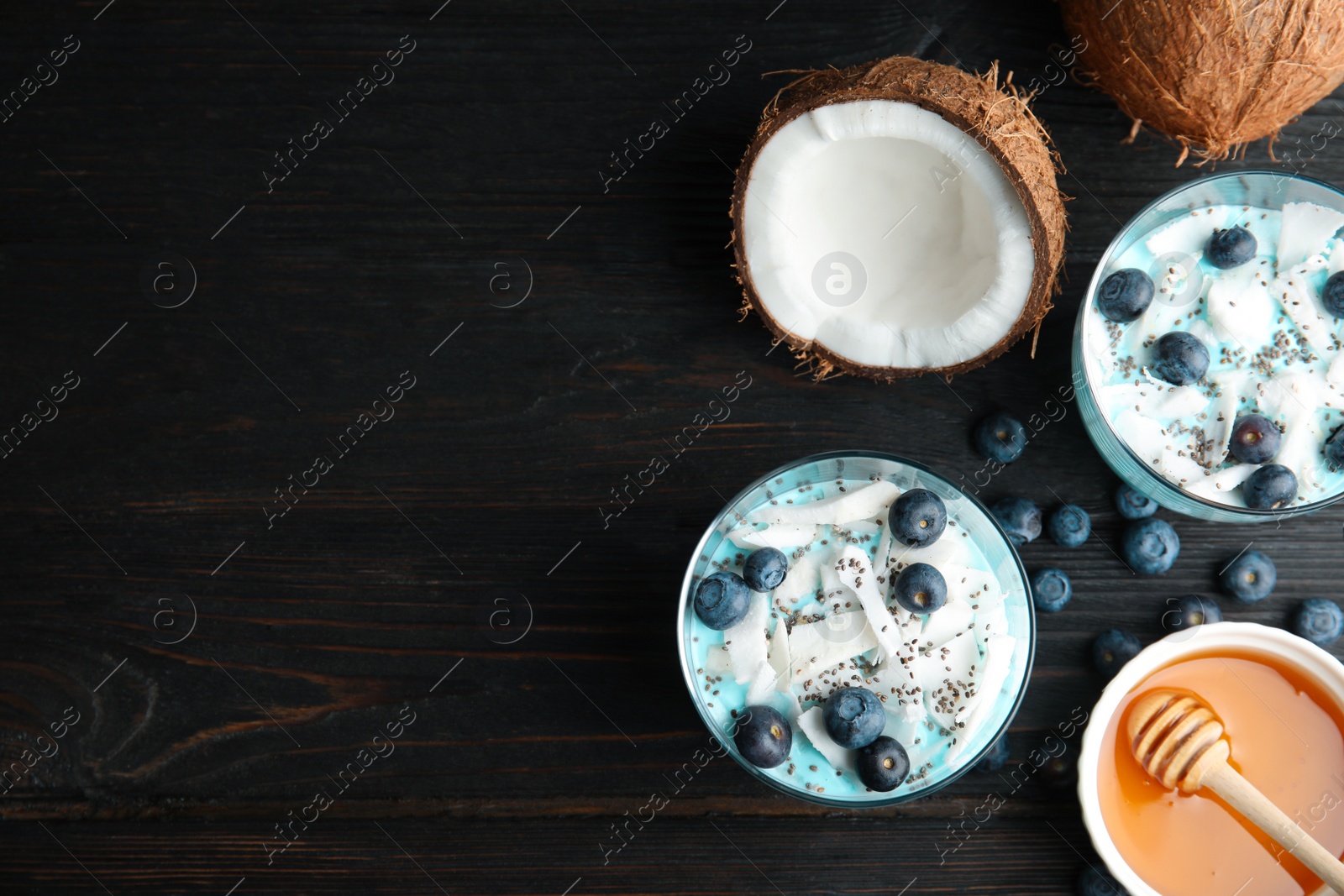 Photo of Flat lay composition with glass cups of spirulina smoothie and space for text on black background