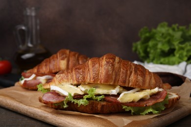 Photo of Tasty croissant with brie cheese and bacon on table, closeup