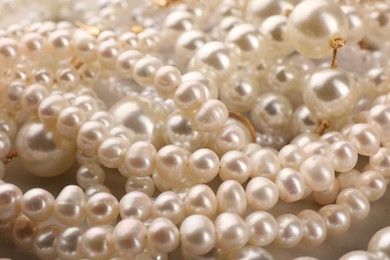 Elegant pearl necklaces as background, closeup view