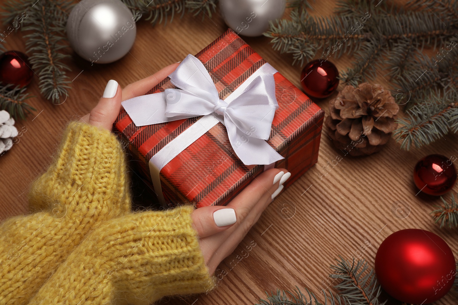 Photo of Woman with Christmas gift at wooden table, closeup