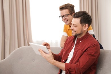 Happy father and his teenager son with tablet computer at home