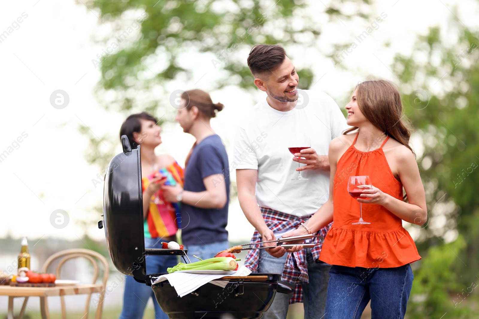 Photo of Young people having barbecue with modern grill outdoors