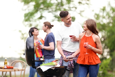 Young people having barbecue with modern grill outdoors