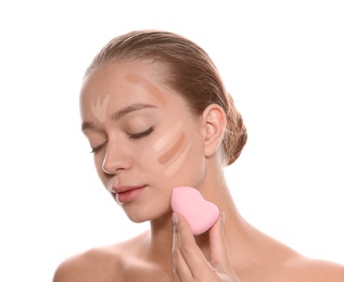 Photo of Young woman applying foundation on her face against white background