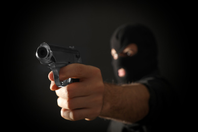 Photo of Professional killer on black background, focus on gun