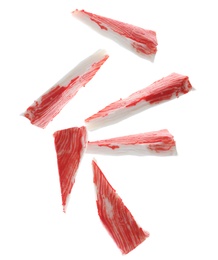 Cut fresh crab sticks falling on white background