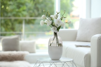 Photo of Vase with fresh flowers on white table in living room