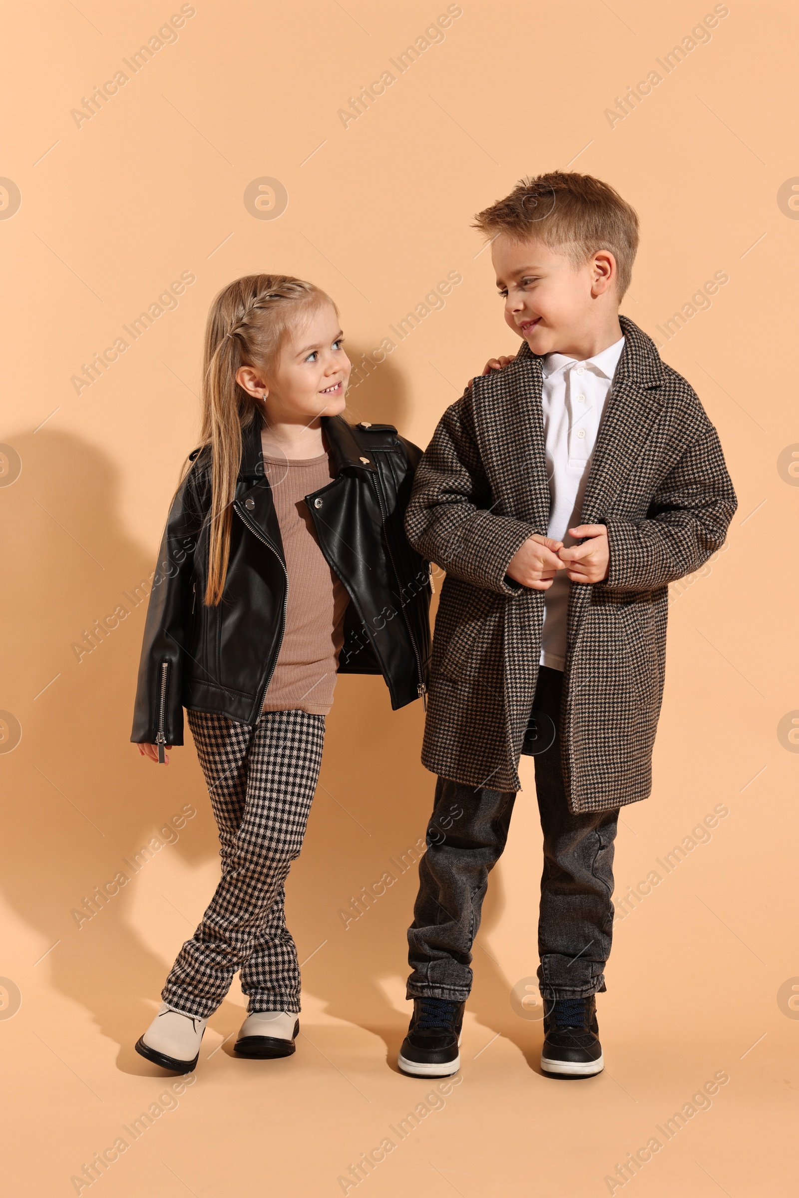 Photo of Fashion concept. Stylish children posing on pale orange background