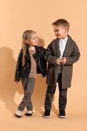 Photo of Fashion concept. Stylish children posing on pale orange background