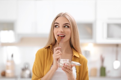 Young woman with yogurt on blurred background