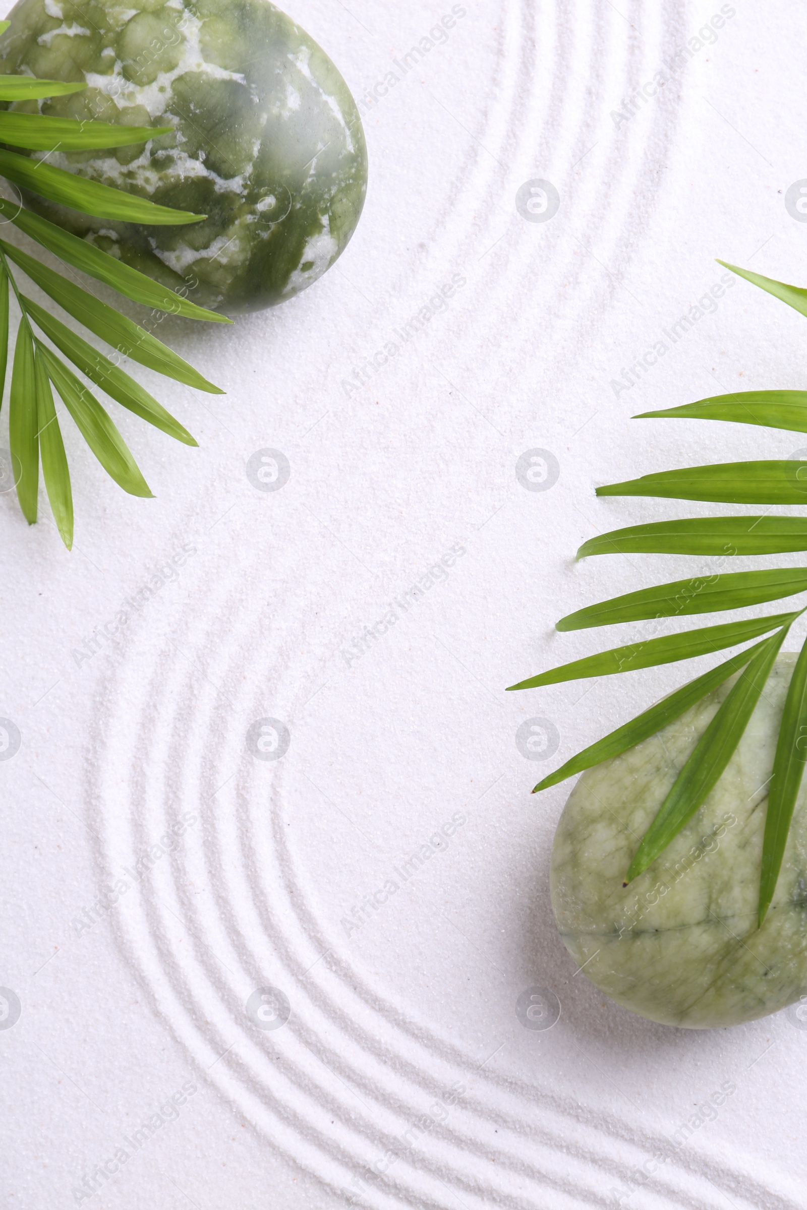 Photo of Zen concept. Stones, leaves and pattern on white sand, flat lay