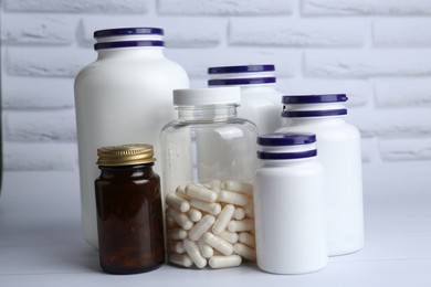 Photo of Different medical bottles on white wooden table