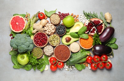 Different vegetables, seeds and fruits on grey table, flat lay. Healthy diet