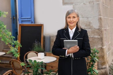 Photo of Happy business owner with tablet near her cafe outdoors, space for text