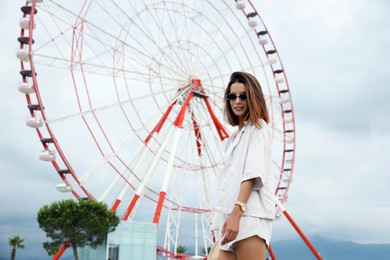 Photo of Beautiful young woman near Ferris wheel outdoors