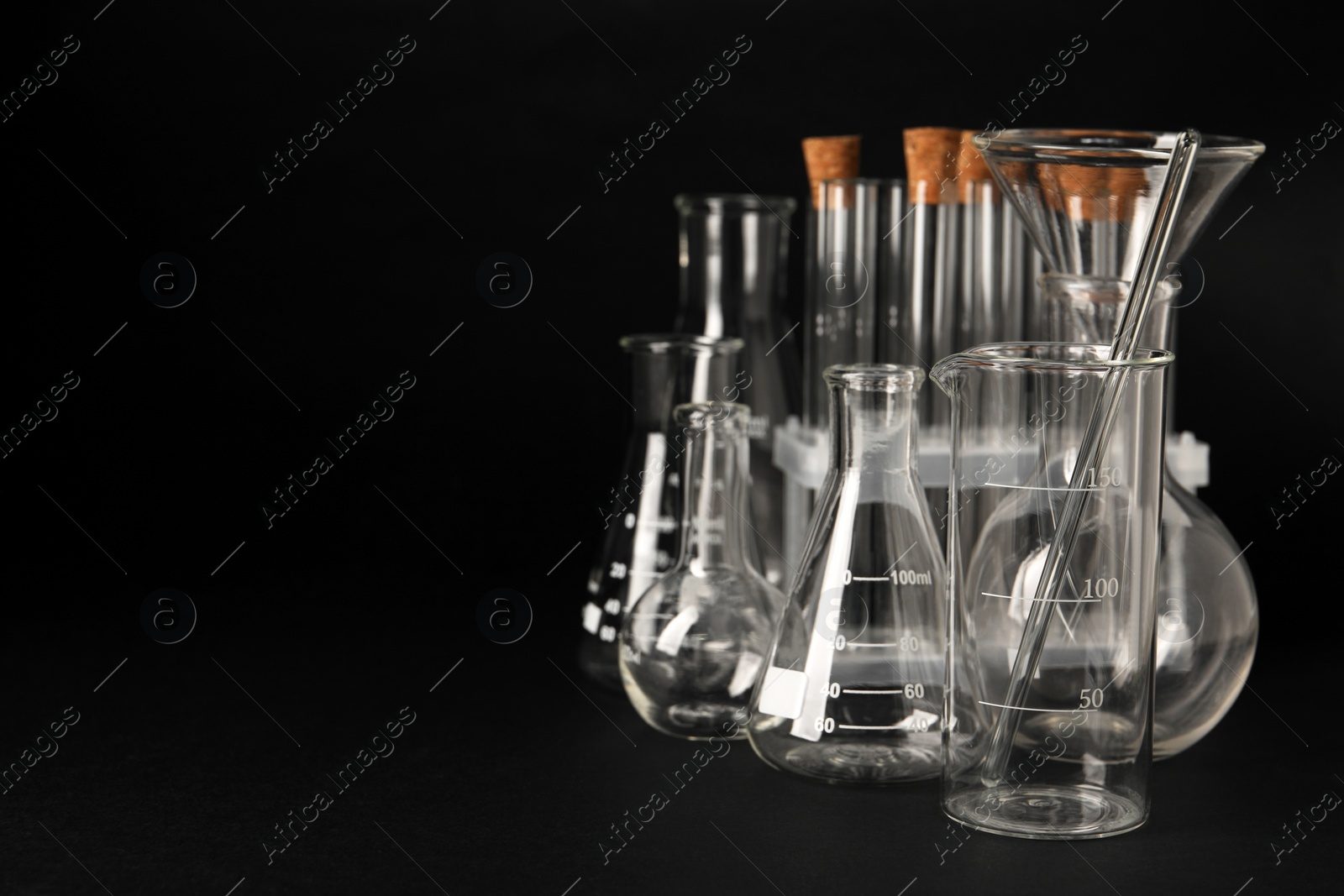 Photo of Different laboratory glassware on black background, space for text