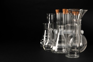 Photo of Different laboratory glassware on black background, space for text