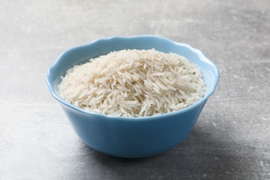 Photo of Raw basmati rice in bowl on grey table, closeup