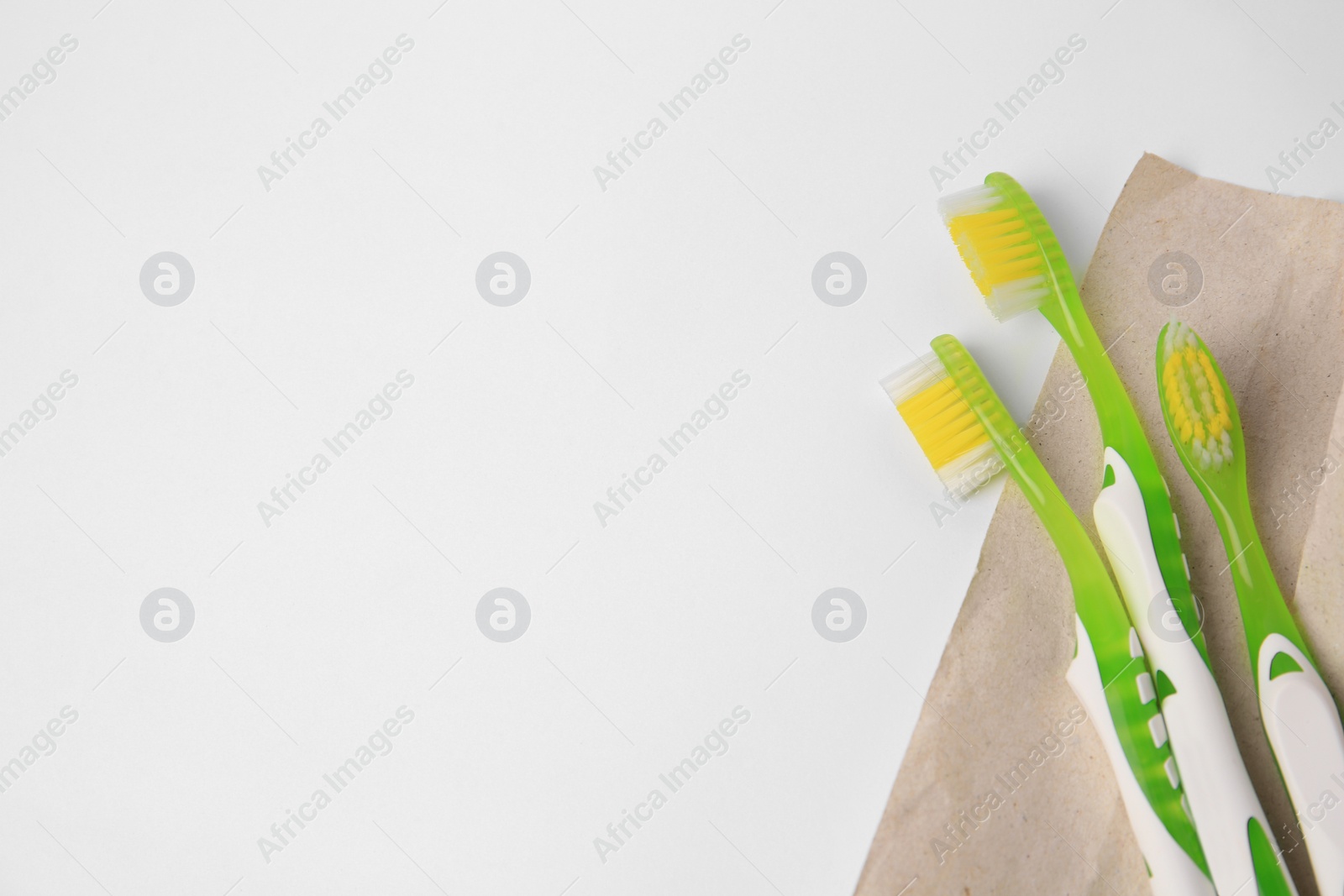 Photo of Light green toothbrushes on white background, top view. Space for text