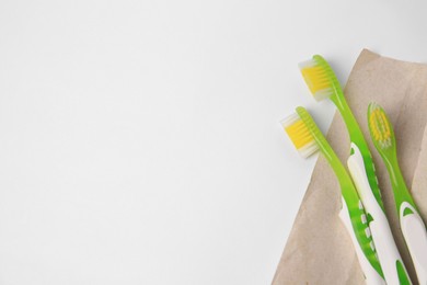 Light green toothbrushes on white background, top view. Space for text