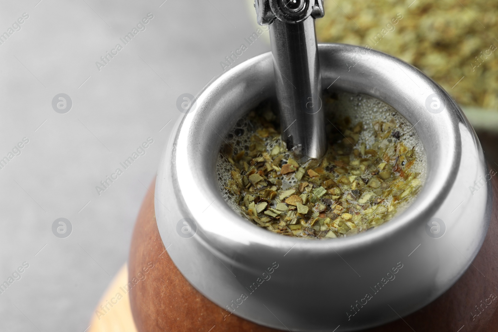 Photo of Calabash with bombilla and mate tea on grey table, closeup