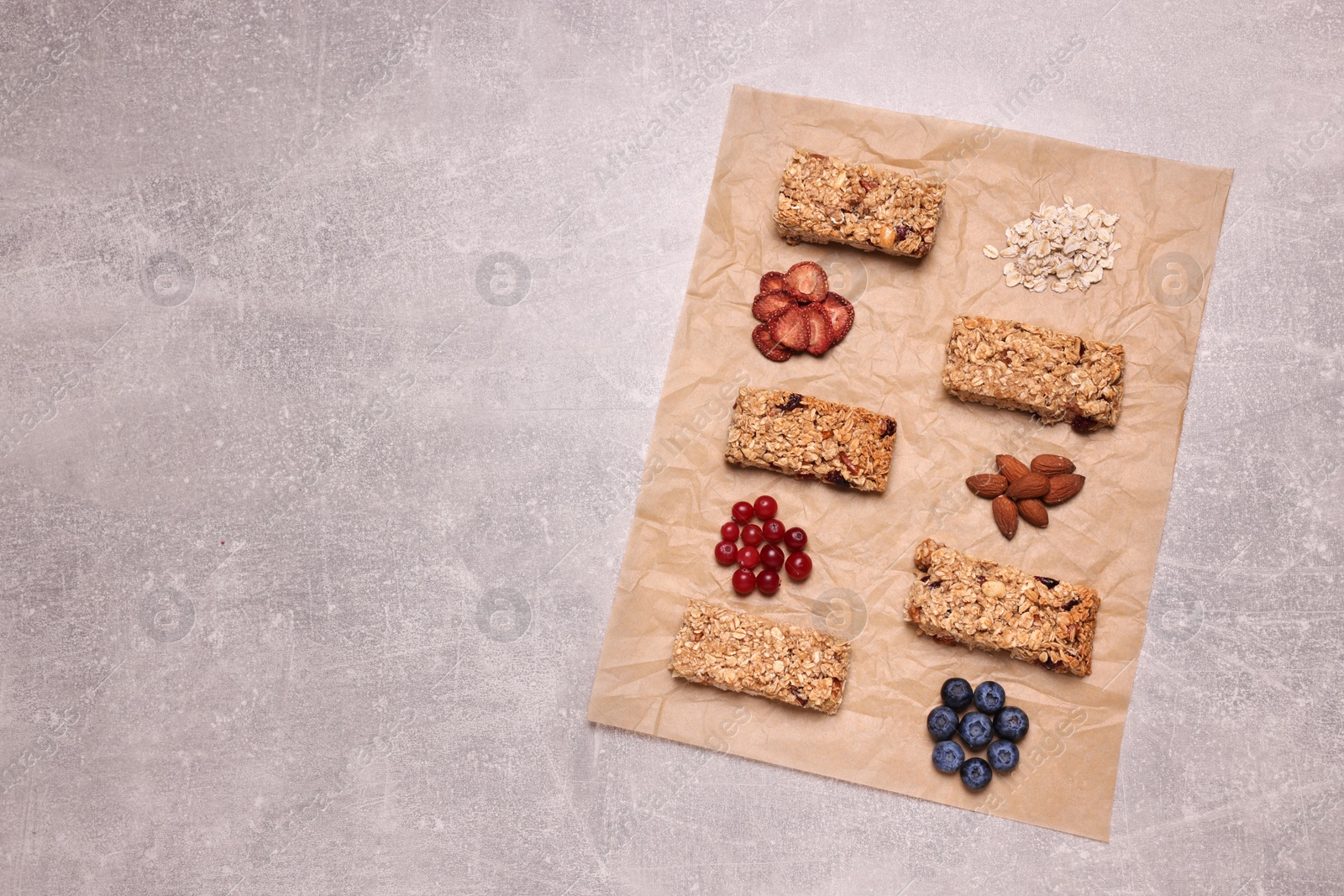 Photo of Different tasty granola bars and ingredients on light grey background, flat lay. Space for text