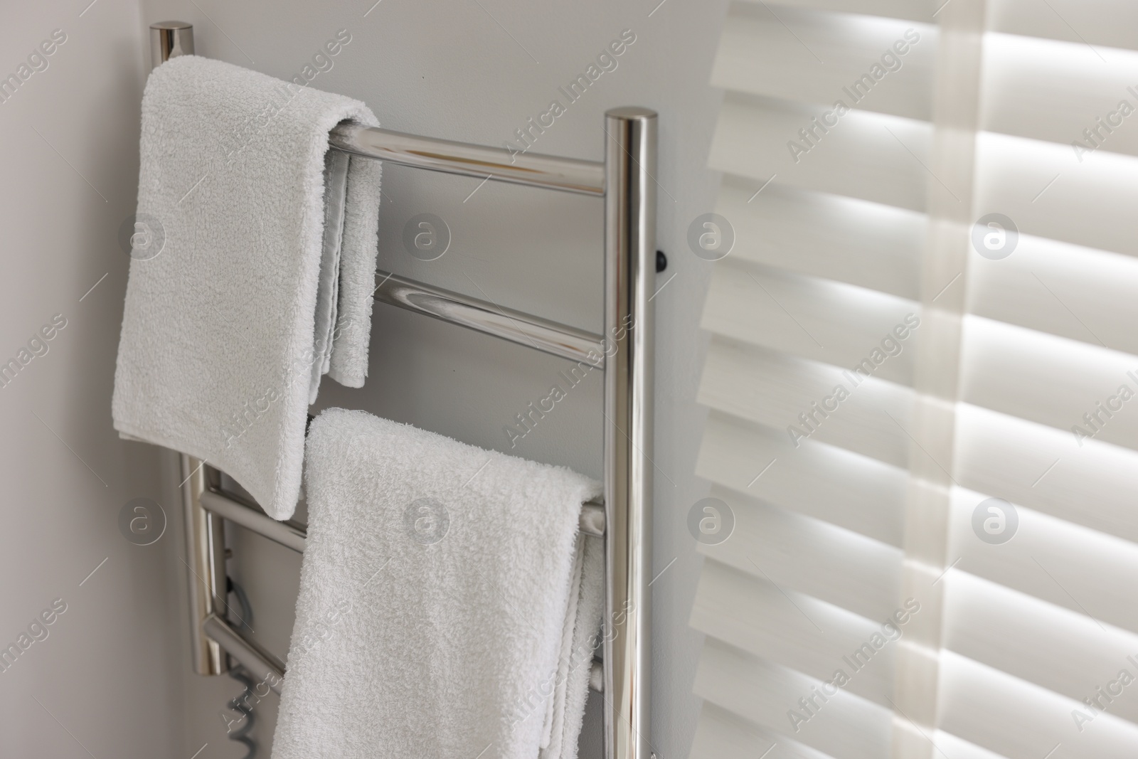 Photo of Heated towel rail with towels in bathroom