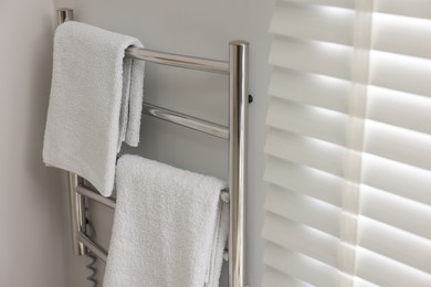 Photo of Heated towel rail with towels in bathroom