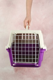 Photo of Woman holding violet pet carrier against pink wall, closeup