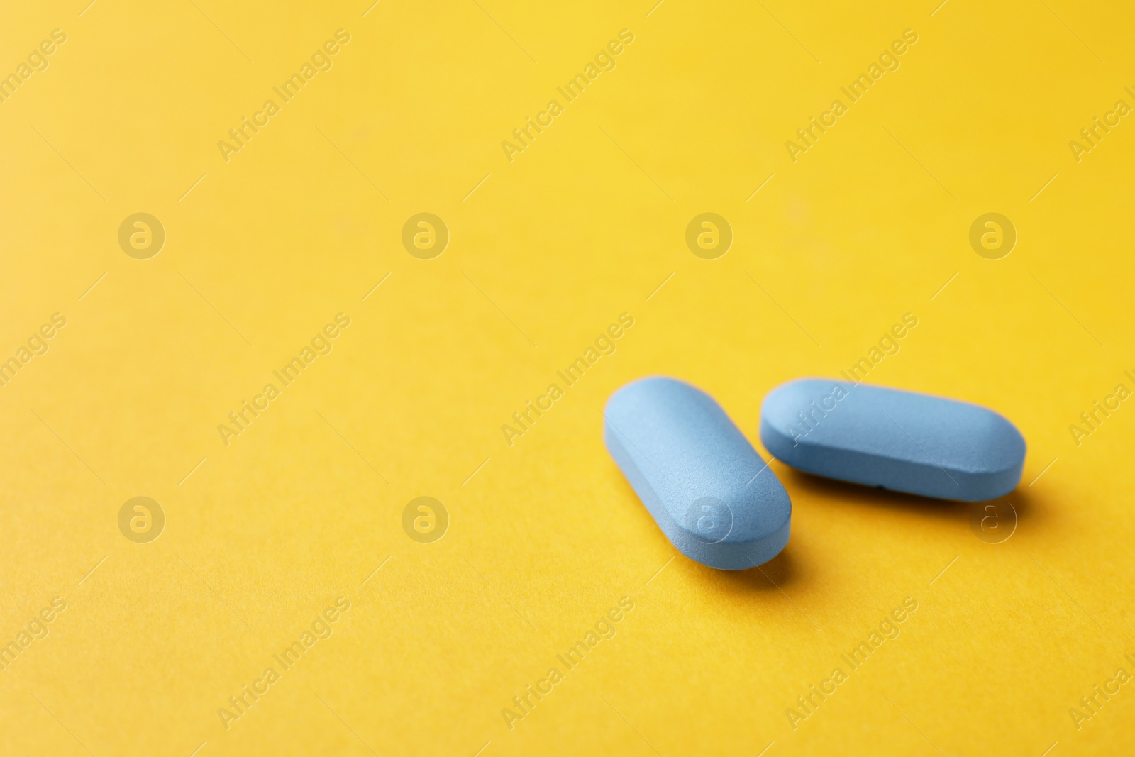 Photo of Pills on orange background, space for text. Potency problem