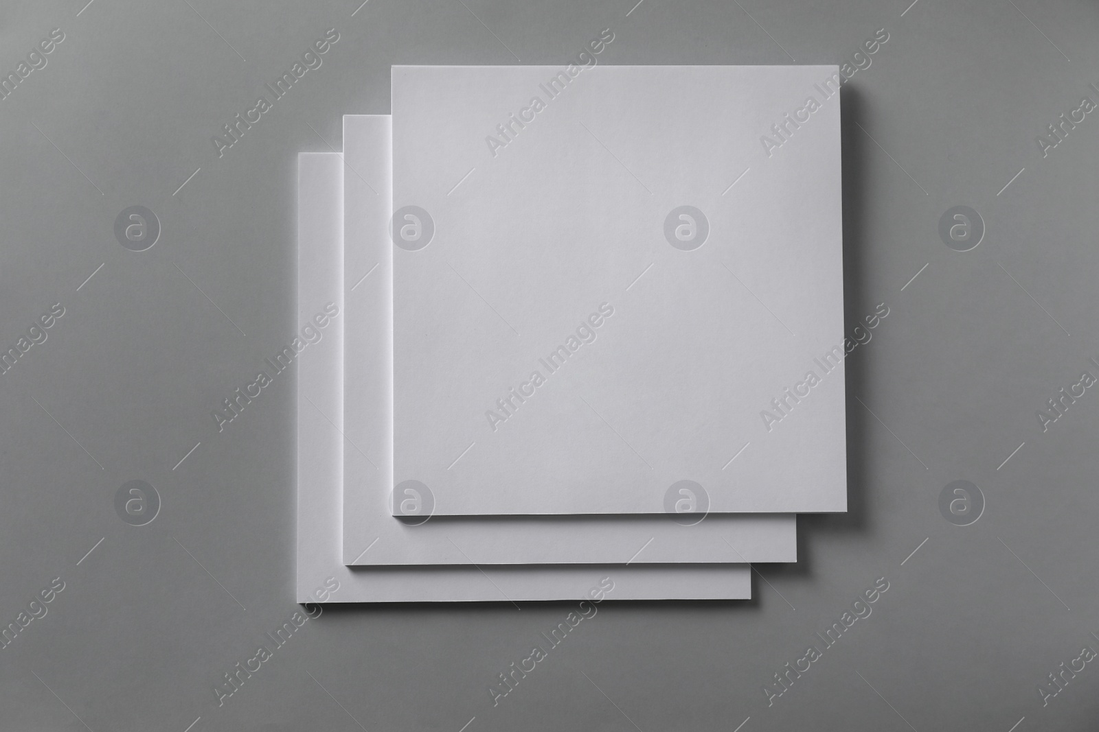 Photo of Stack of blank paper sheets for brochure on light grey background, top view