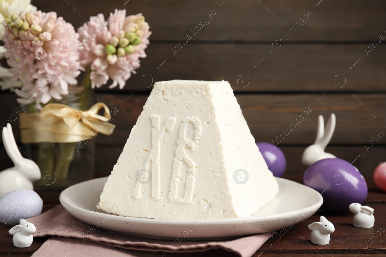 Photo of Traditional cottage cheese Easter paskha, painted eggs and decorative bunnies on wooden table